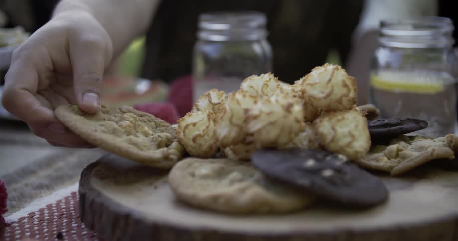 Person choosing a large cookie from an assortment of them on a display
