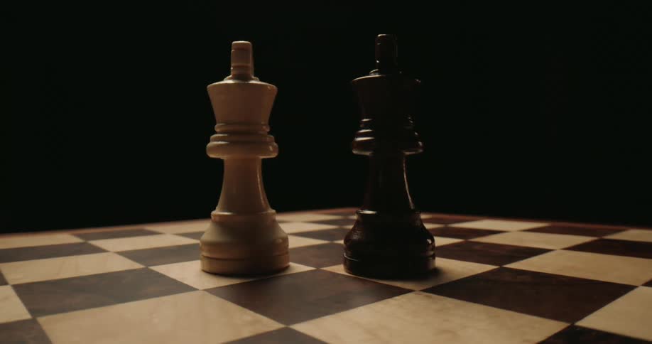 This video features a closeup lowangle shot of a white king and a black king standing together on a chessboard the camera slowly revolves around the two pieces against a dark moody background emphasizing their detail and the tension of the game