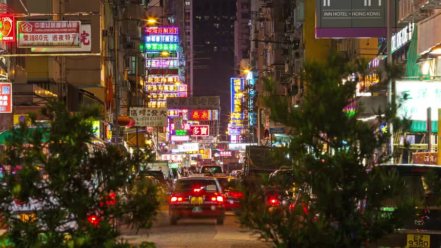 A time lapse shot of a busy city street at night filled with colorful neon signs and moving traffic