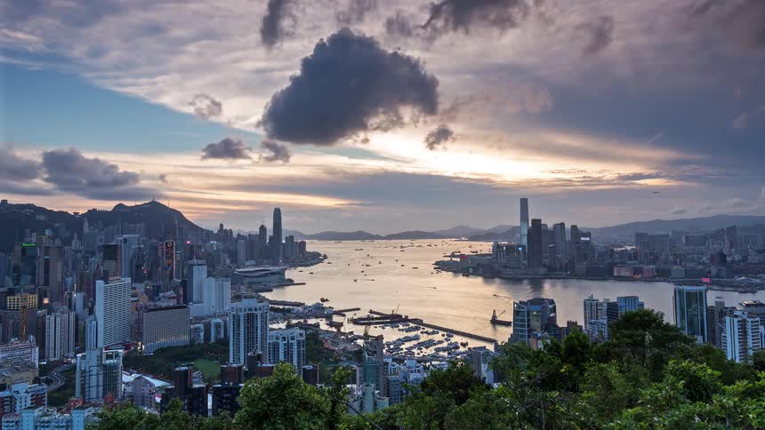 A time lapse shows the sun set over a metropolitan city next to the water