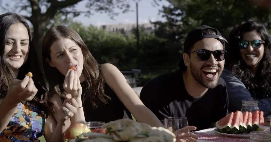 Group of people sitting at picnic table outside laughing together