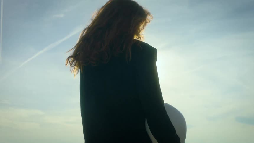 Young female standing up outdoors and tossing her head to the back during day time