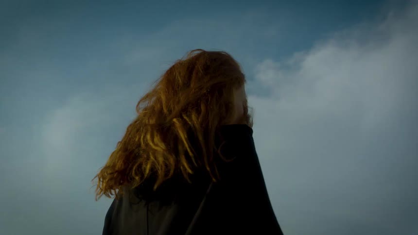 A woman with red hair runs while carrying a white object under her arm