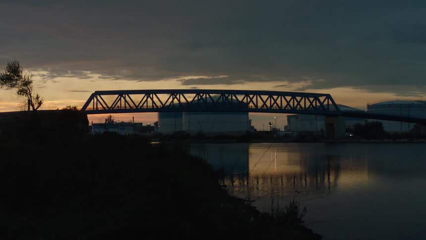 The cars drive by the bridge at sunrise