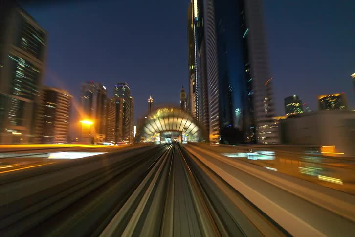 The train moves through the city at night
