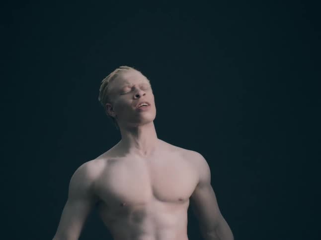 A young male shirtless on a stage performing