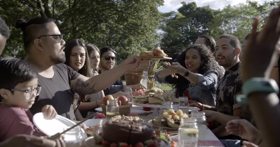 A group gathers around an outdoor picnic table to eat