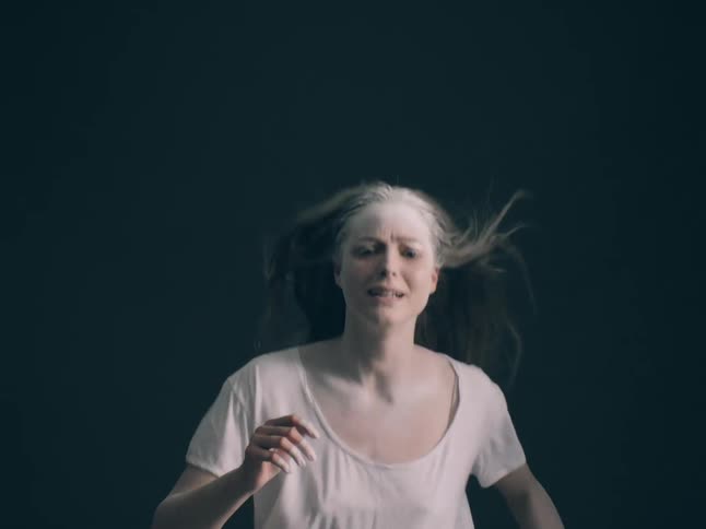 A woman running towards the camera looking sad
