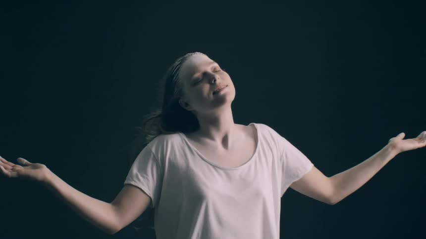 Young adult woman with white powder over her forehead wearing a white shirt and standing with her arms outstreched