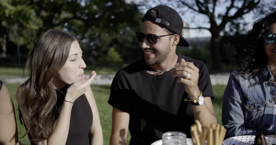 Man feeds woman food outside at a picnic