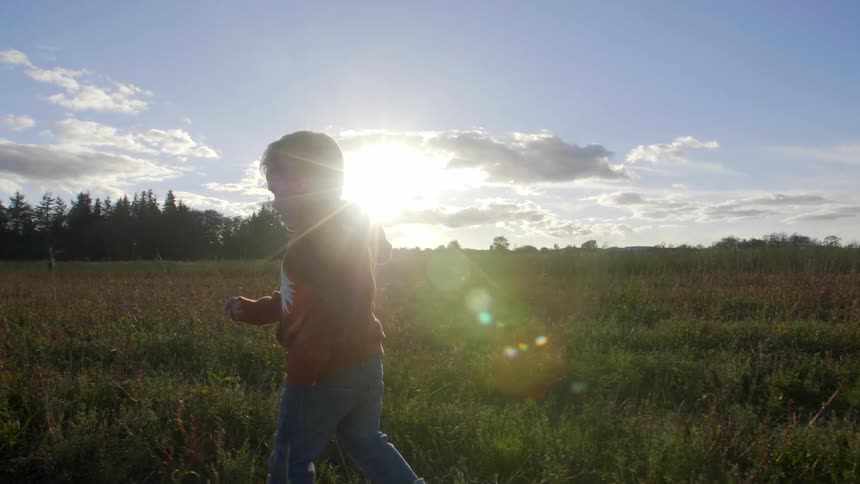 Child runs through the field on a sunny day