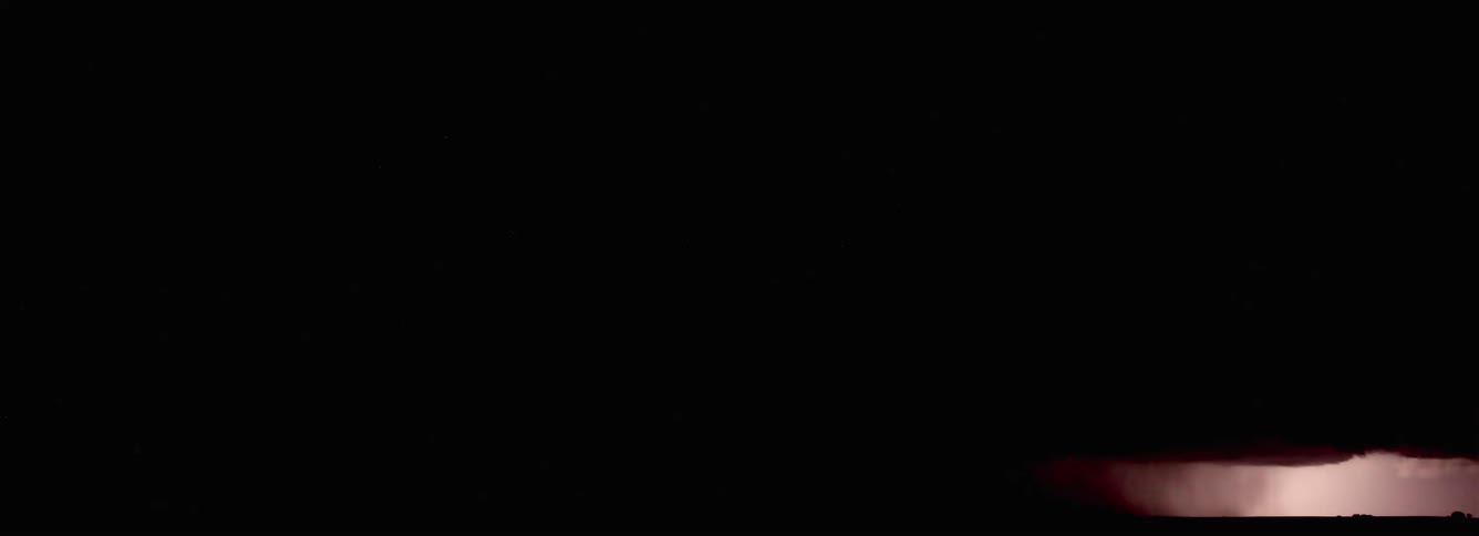 Lightning flashes illuminating dark storm clouds across the night sky