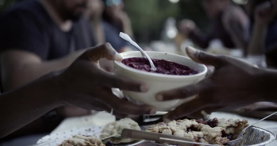 Person passing a bowl to another person at a table with lots of food