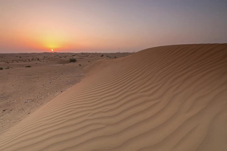 The sun sets over a desert landscape