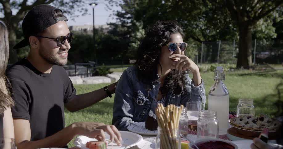 People sitting outside at picnic table are talking and laughing together