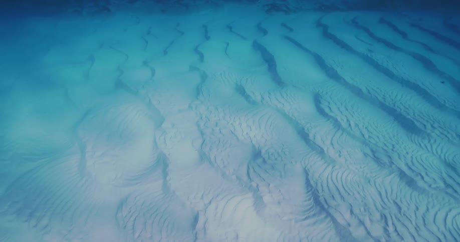 Reflection of clear water ripples over textured underwater sand patterns