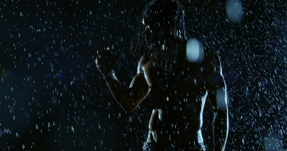 Wet bare chested man holds a seashell in his hand as lightning flashes and rain falls