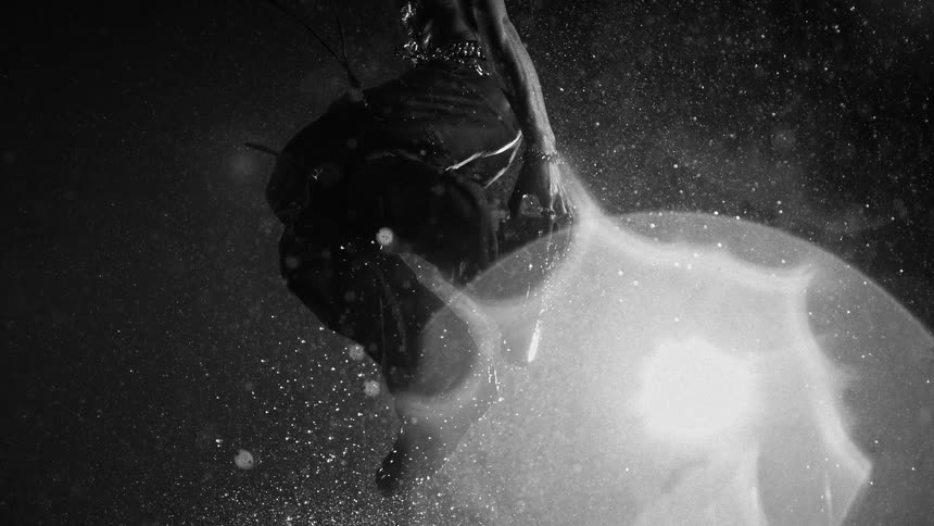 Man jumps under heavy rain with illuminated water particles around him