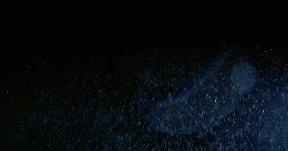 Water particles suspended in the air with blue light beams against a dark background