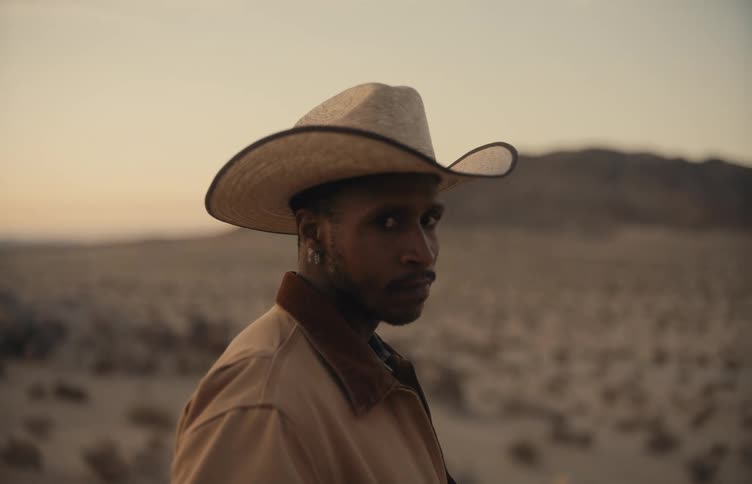 Man standing in the desert wearing a jacket stares as red tints the sky