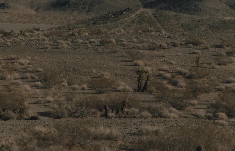 Arid land borders the hills and mountains under a cloudy sky