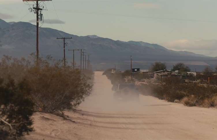 A jeep is moving down a dirt road in the mountains