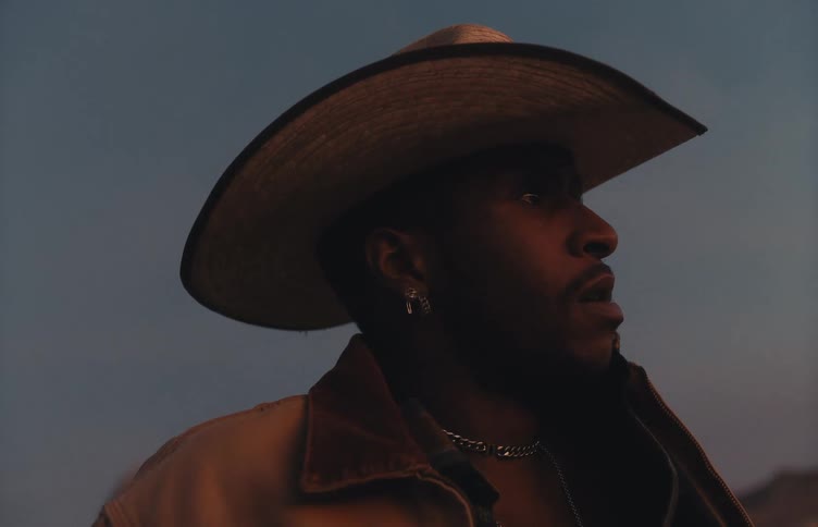 A portrait of a man outdoors wearing a cowboy hat