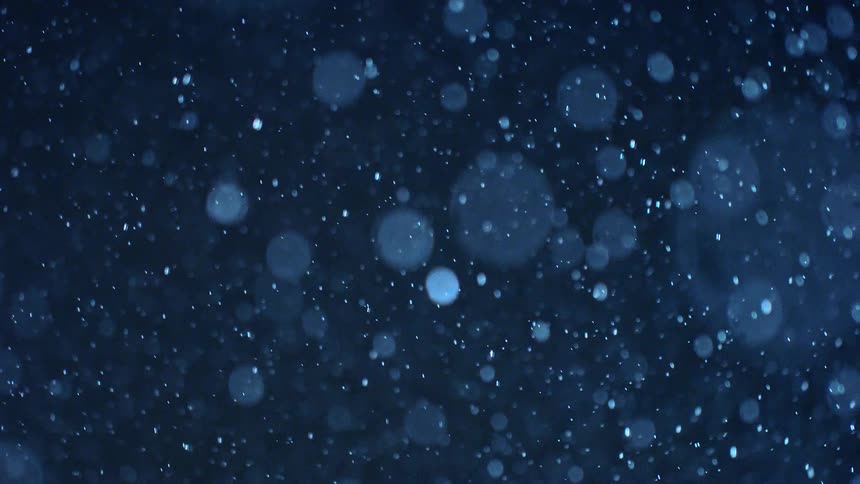 A view of some snow falling outdoors at night