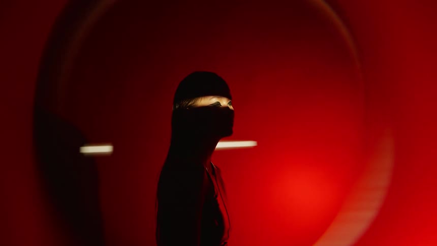 Woman gazes under intense red lighting with a circular effect around her