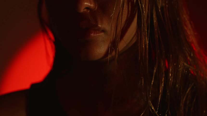 A close up of a womans wet face and hair with red lighting