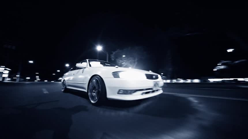 White car travels on a city street at night