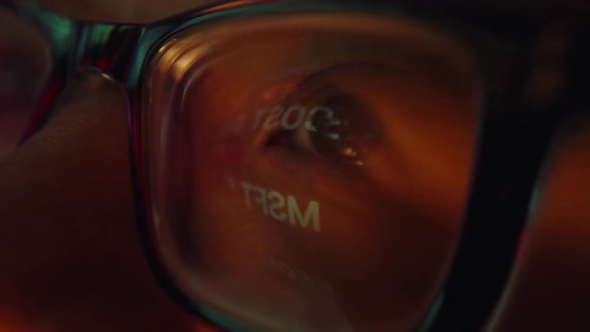Closeup of eye reflected in eyeglass lens under warm lighting