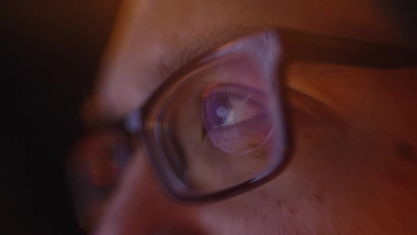 Lights reflect off a mans glasses