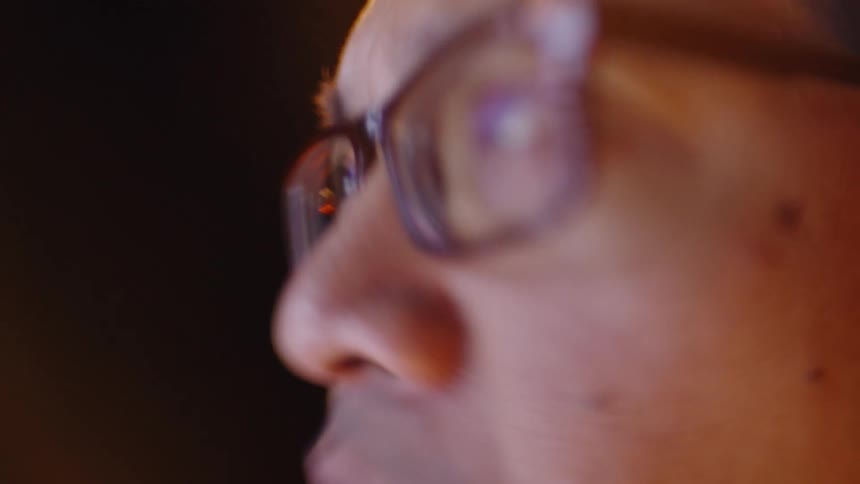Eye of a person wearing glasses reflecting bluish screen light