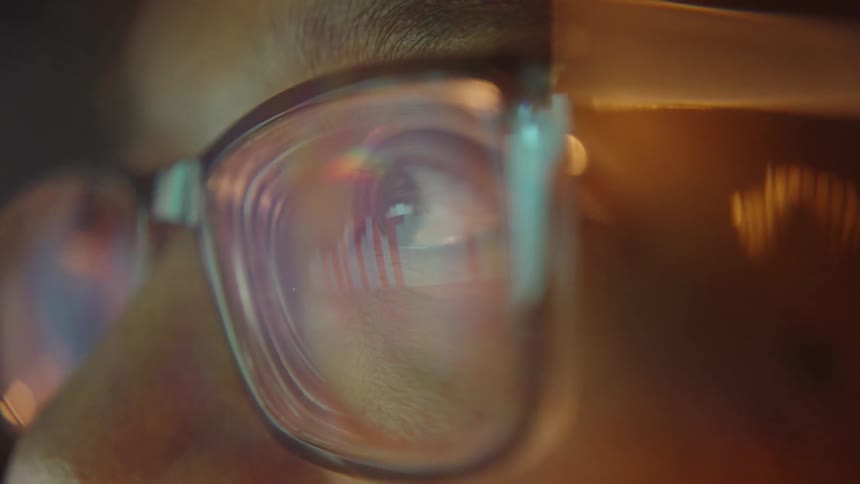 Light reflects on the mans glasses