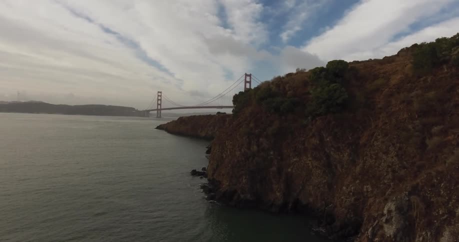 The golden gate bridge spans across the water under cloudy skies