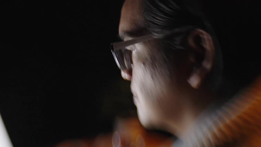 A man wearing glasses is looking at a laptop screen
