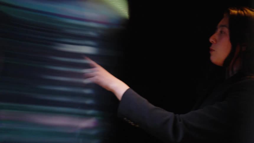 The woman is pointing at a display and talking