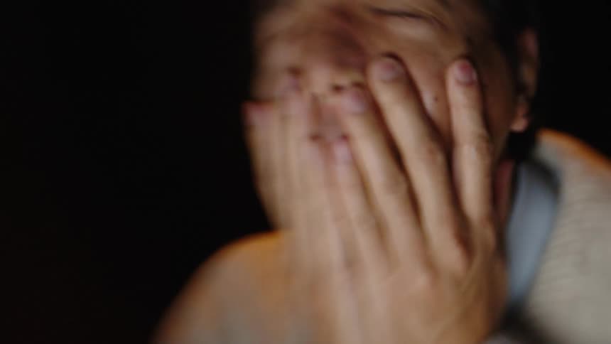 A man in a room rubbing his face