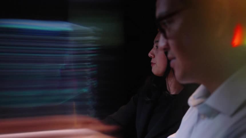 A man and woman are looking at graphs on a screen
