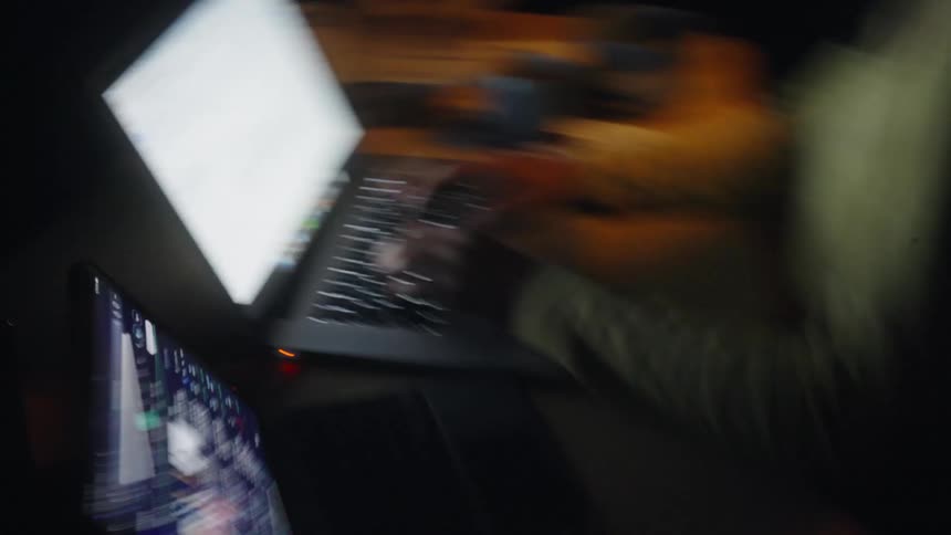 Woman typing on a keyboard backlit by a laptop screen in use