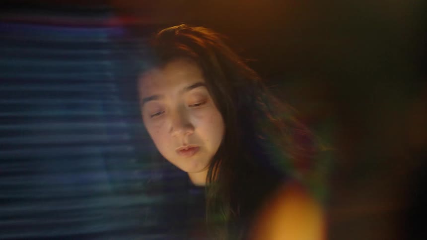 A woman looks at a screen displaying financial data with glitch effects and light flares