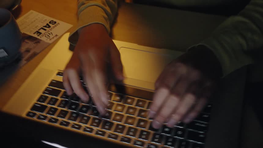 Hands typing on illuminated laptop keyboard