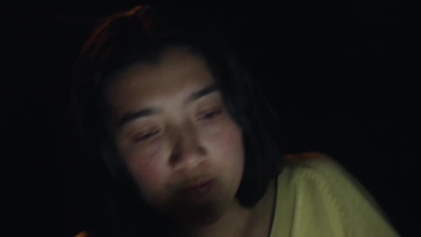 Woman wearing a yellow shirt holding a blue mug in a dark environment