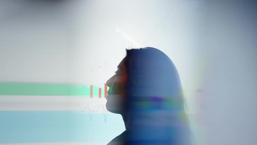 A persons silhouette is overlaid with financial charts