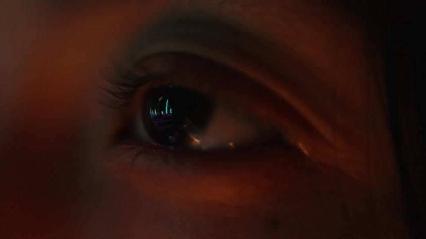 An extreme closeup of aapersons eye illuminated by warm amber light with colorful reflections visible in the pupil