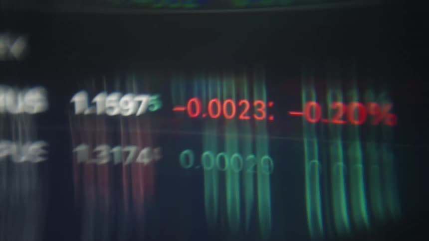 A close up view of a digital screen displays financial market data with numbers and percentages changing