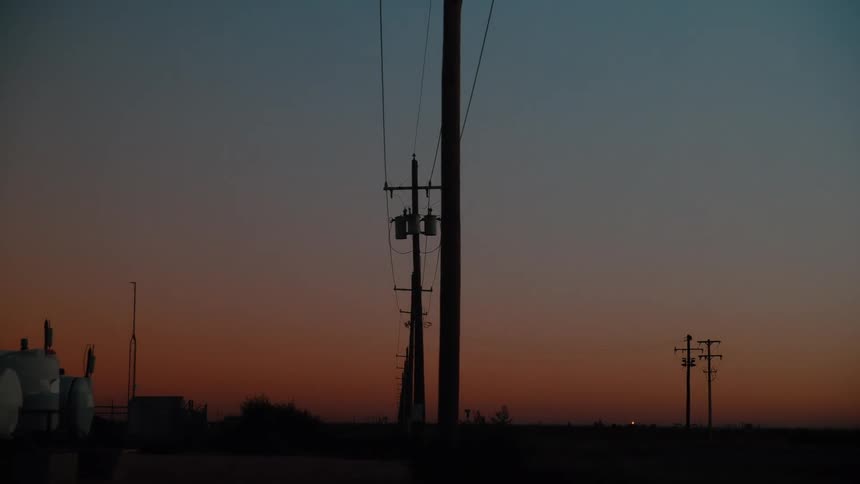 The sun is rising on the row of power lines