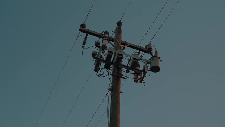 A utility pole holding a series of power lines at sunset