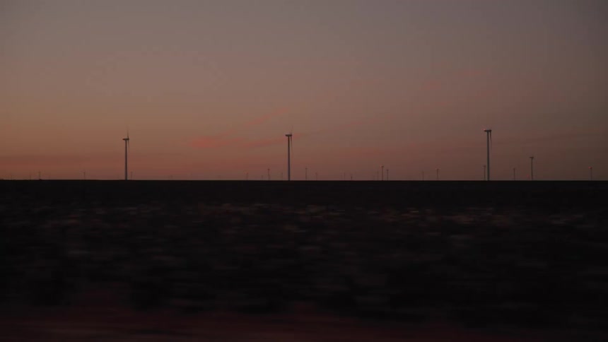 Silhouettes of wind turbines on the horizon at dusk